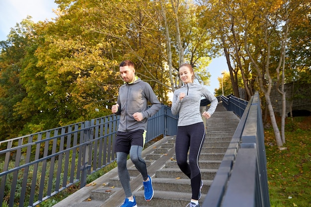 Zdjęcie koncepcja fitness, sportu, ludzi i stylu życia - szczęśliwa para biegająca po dole w mieście