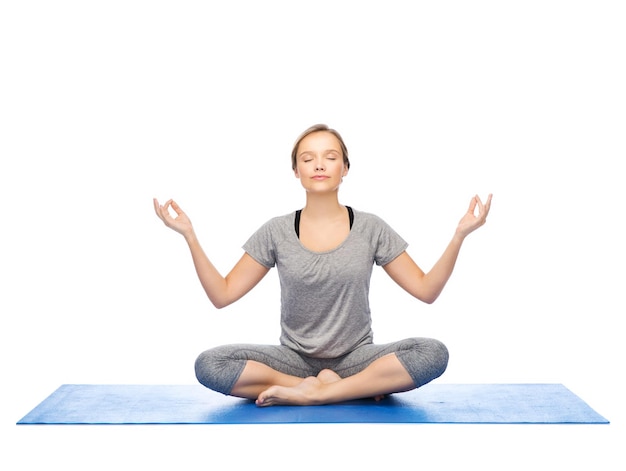 koncepcja fitness, sportu, ludzi i zdrowego stylu życia - kobieta robi medytację jogi w pozycji lotosu na macie