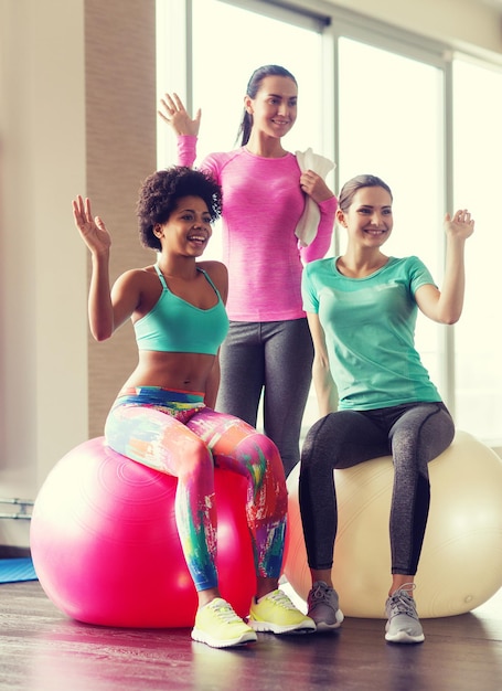 koncepcja fitness, sportu, treningu i stylu życia - grupa uśmiechniętych kobiet z piłkami do ćwiczeń w siłowni
