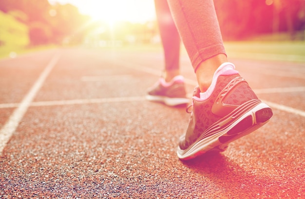 koncepcja fitness, sportu, treningu, ludzi i stylu życia - zbliżenie kobiecych stóp biegnących po torze od tyłu