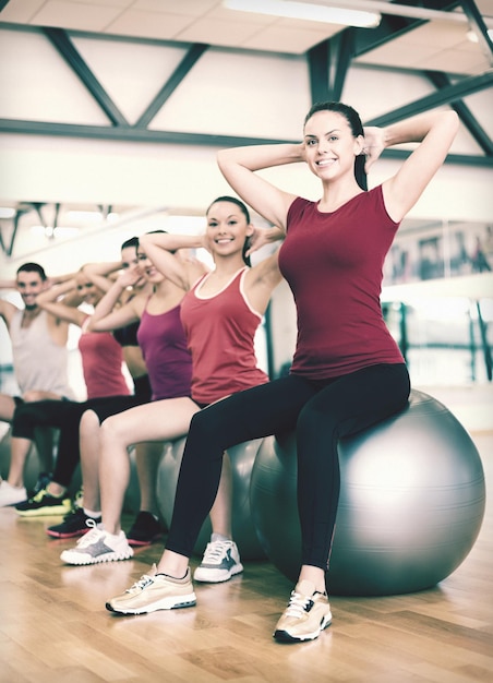 koncepcja fitness, sportu, treningu, siłowni i stylu życia - grupa uśmiechniętych ludzi ćwiczących na zajęciach pilates