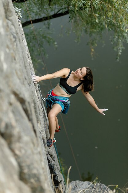 Koncepcja fitnessu, sportów ekstremalnych i zdrowego stylu życia - Climber pokonuje trudne trasy wspinaczkowe. Dziewczyna wspina się na skałę. Kobieta uprawiająca sport ekstremalny. Ekstremalne hobby.