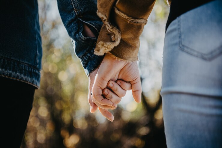Zdjęcie koncepcja gejów, lgbt i homoseksualizmu - zbliżenie szczęśliwa para lesbijek, trzymając się za ręce na tle trawy - obraz czasowy