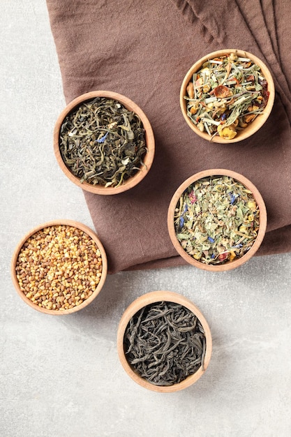 Koncepcja gotowania herbaty z różnymi rodzajami herbaty na jasnym tle z teksturą
