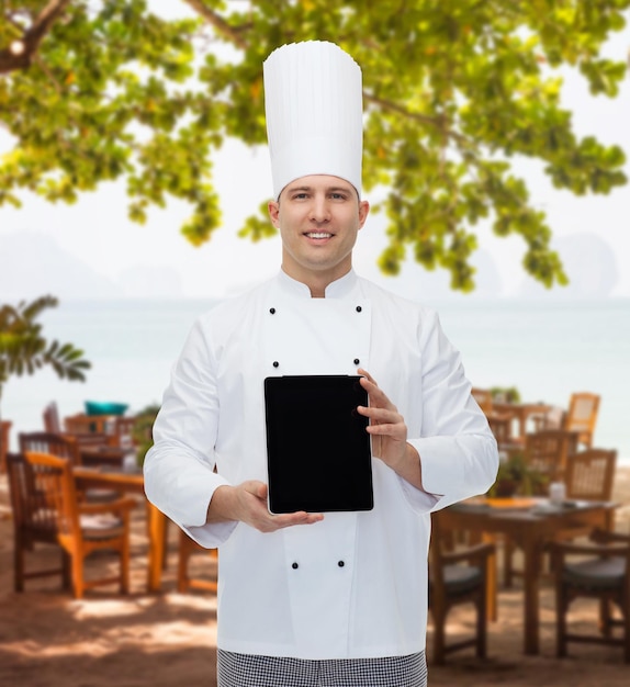 koncepcja gotowania, zawodu i ludzi - szczęśliwy mężczyzna kucharz kucharz pokazujący komputer typu tablet pc czarny pusty ekran nad salonem restauracyjnym na plaży