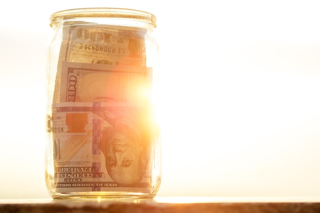 Koncepcja gromadzenia pieniędzy w szklanym słoiku w słońcu za pomocą słońca
