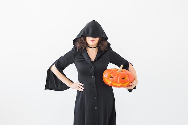 Koncepcja Halloween - Anonimowa wiedźma z dyniową latarnią na jasnej ścianie