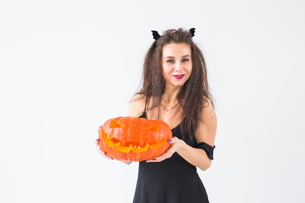 Koncepcja Halloween i maskarady - piękna młoda kobieta pozuje z dyni Jack-o'-lantern