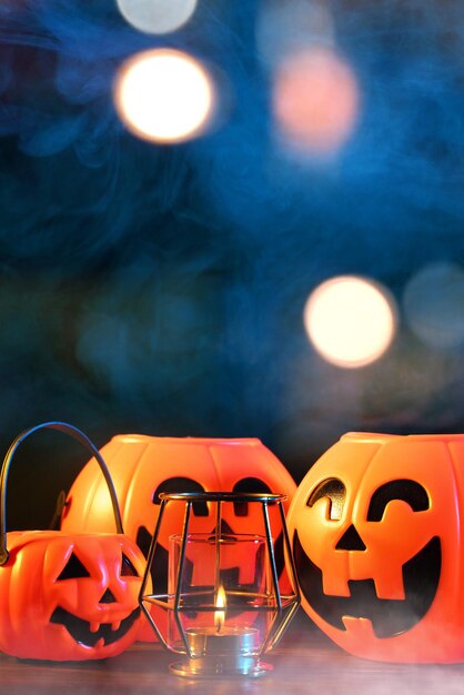 Koncepcja Halloween Pomarańczowa plastikowa latarnia z dyni na ciemnym drewnianym stole z rozmytym błyszczącym światłem w tle Cukierek albo psikus z bliska