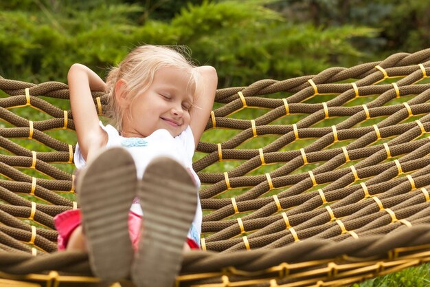 Koncepcja Happy Summer Vacation Mała dziewczynka Dziecko z zamkniętymi oczami leżące w hamaku w zielonym ogrodzie
