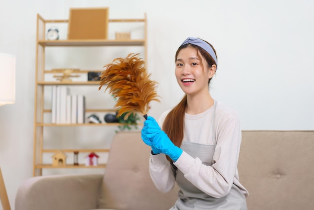 Koncepcja higienicznego sprzątania Pokojówka nosi rękawiczki i trzyma miotełkę z piór do sprzątania domu