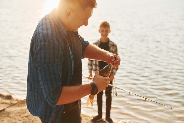Koncepcja hobby Ojciec i syn podczas wspólnego łowienia ryb na świeżym powietrzu w okresie letnim