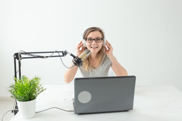 Koncepcja hosta radiowego - kobieta pracująca jako gospodarz radiowy siedzi przed mikrofonem na białym