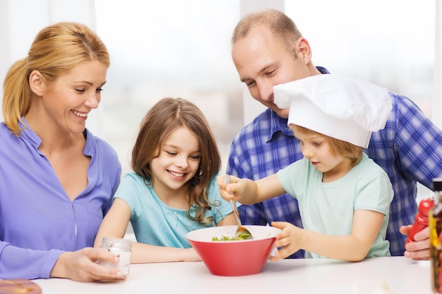 koncepcja jedzenia, rodziny, dzieci, szczęścia i ludzi - szczęśliwa rodzina z dwójką dzieci robi obiad w domu