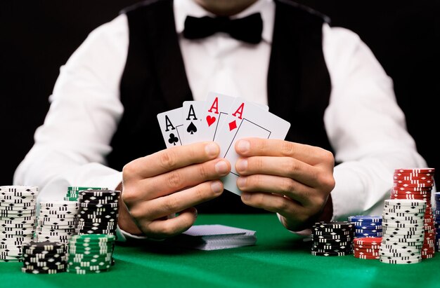 koncepcja kasyna, hazardu, pokera, ludzi i rozrywki - zbliżenie pokerzysty z kartami do gry i żetonami przy zielonym stole w kasynie