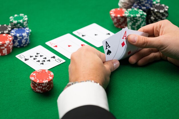 Koncepcja Kasyna, Hazardu, Pokera, Ludzi I Rozrywki - Zbliżenie Pokerzysty Z Kartami Do Gry I żetonami Przy Zielonym Stole W Kasynie