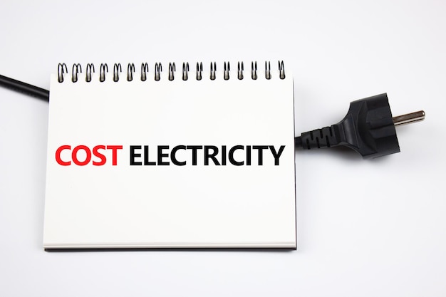 Koncepcja kosztów energii elektrycznej Napis KOSZT ENERGII ELEKTRYCZNEJ na kartce papieru i wtyczce elektrycznej