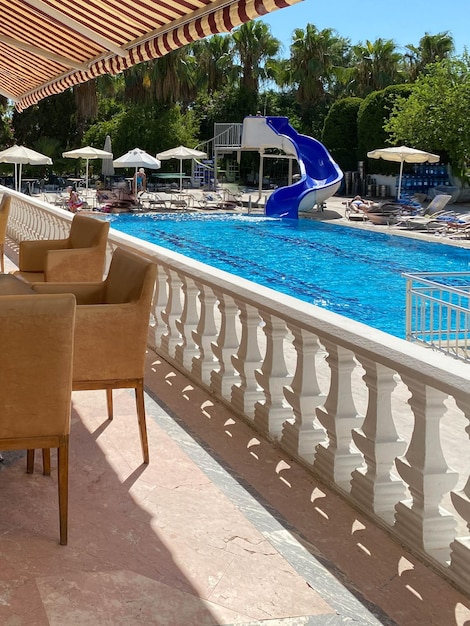 Koncepcja krzeseł relaksacyjnych i stołów białych parasoli od słońca wokół basenu