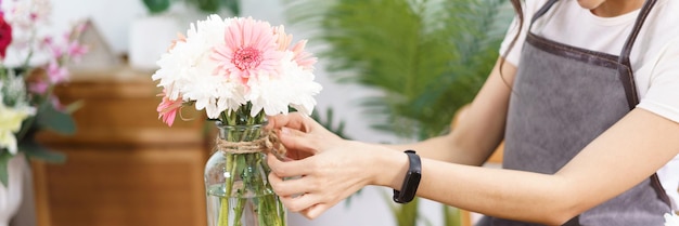 Koncepcja kwiaciarni Kobieca kwiaciarnia dekoruje kolorowy wazon z kwiatami liną konopną w kształcie kokardki