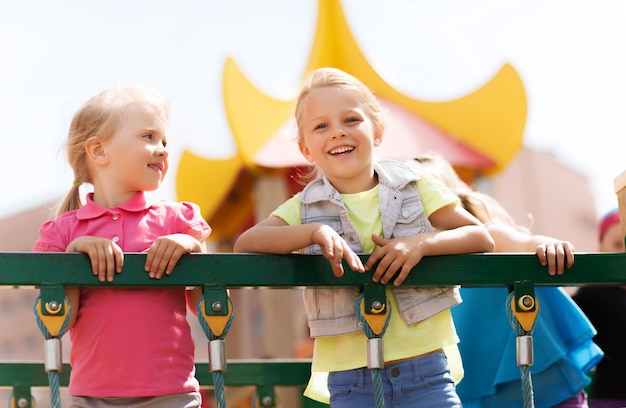 koncepcja lato, dzieciństwo, wypoczynek, przyjaźń i ludzie - szczęśliwe dziewczynki na placu zabaw dla dzieci