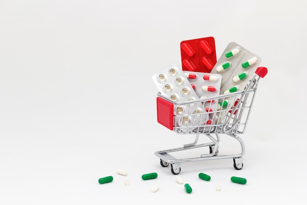 Koncepcja leku Kapsułki i tabletki w wózku sklepowym na białym tle Kup lek