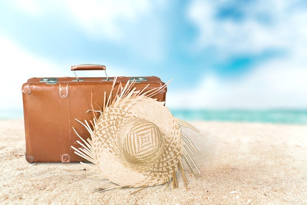 Koncepcja letnich podróży ze starą walizką i akcesoriami. Rozmycie plaży w tle