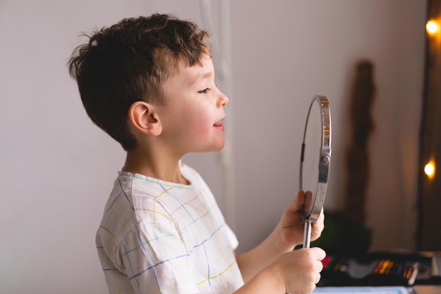 Koncepcja logopedii Śliczny mały chłopiec wymawia dźwięk O patrząc w lustro robi lekcję logopedyczną online za pośrednictwem laptopa