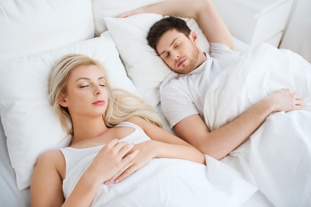 koncepcja ludzi, odpoczynku i relacji - szczęśliwa para śpiąca w łóżku w domu