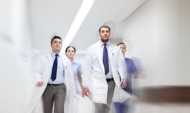 koncepcja ludzi, opieki zdrowotnej i medycyny - grupa lekarzy spacerujących po szpitalu (efekt rozmycia ruchu)