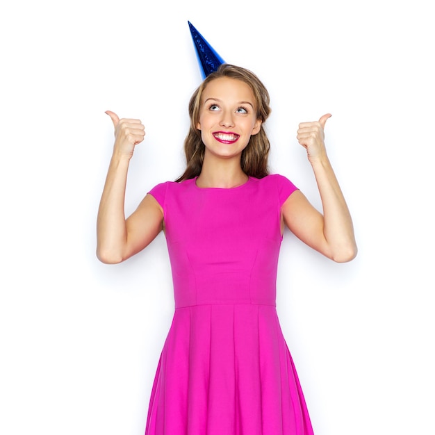 koncepcja ludzi, świąt i uroczystości - szczęśliwa młoda kobieta lub nastolatka w różowej sukience i czapce imprezowej