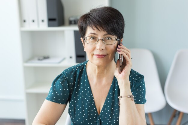 Koncepcja ludzi, technologii i komunikacji - pani biznes dla dorosłych rozmawia przez telefon w biurze.