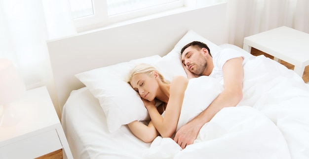 koncepcja ludzie, odpoczynek, relacje i szczęście - szczęśliwa para śpiąca w łóżku w domu