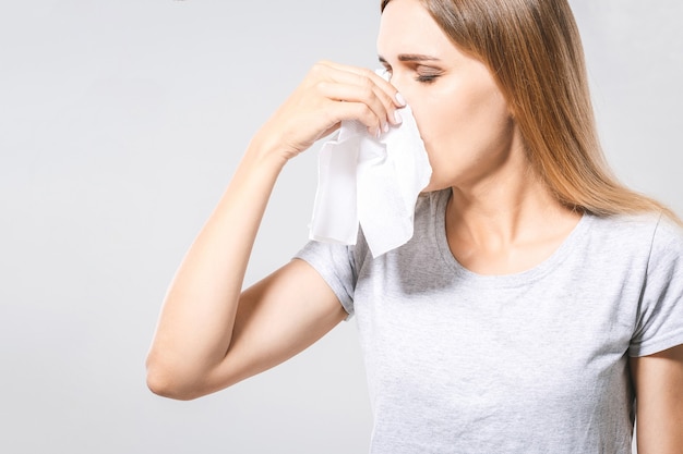 Koncepcja ludzie, opieka zdrowotna, nieżyt nosa, przeziębienie i alergie - nieszczęśliwa kobieta z papierową serwetką dmuchającą nos