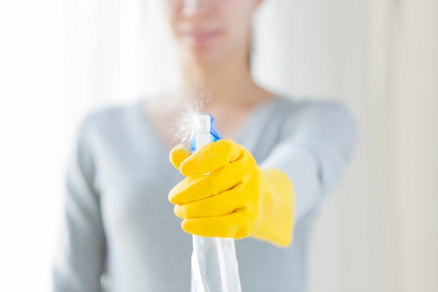 koncepcja ludzie, prace domowe i sprzątanie - zbliżenie szczęśliwej kobiety z środkiem czyszczącym spryskującym dom