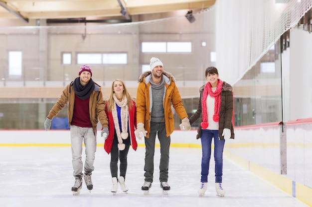 koncepcja ludzie, przyjaźń, sport i rozrywka - szczęśliwi przyjaciele na lodowisku