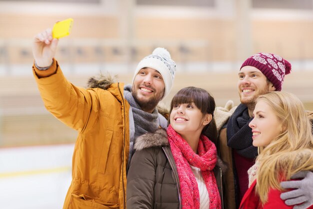 Koncepcja Ludzie, Przyjaźń, Technologia I Rozrywka - Szczęśliwi Przyjaciele Robiący Selfie Ze Smartfonem Na Lodowisku