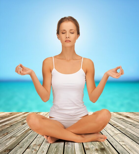 koncepcja ludzie, relaks i zdrowie - kobieta w bieliźnie medytująca w pozycji lotosu jogi