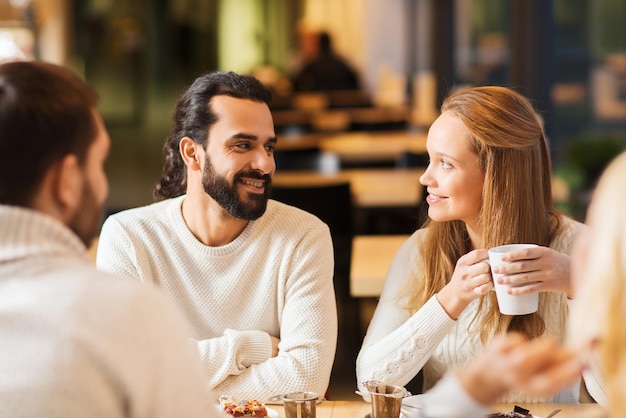 koncepcja ludzie, rozrywka i komunikacja - szczęśliwi przyjaciele spotykają się i piją herbatę lub kawę w kawiarni