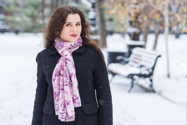 Koncepcja ludzie, sezon i moda - młoda brunetka kobieta w płaszczu pozowanie na zimowej ulicy
