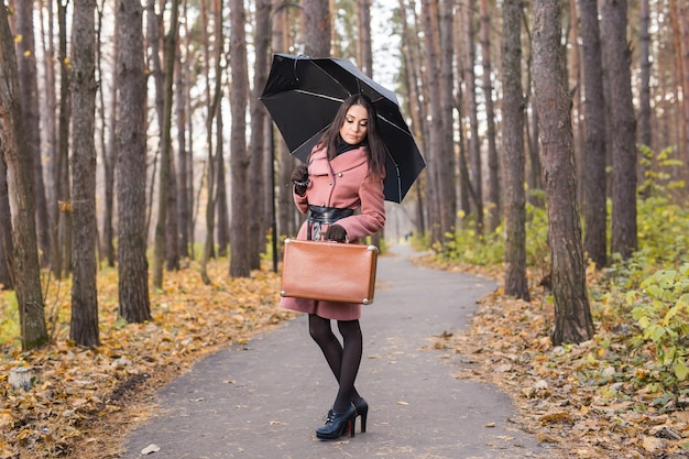 Koncepcja ludzie, sezon i moda - piękna młoda kobieta w parku jesień z parasolem