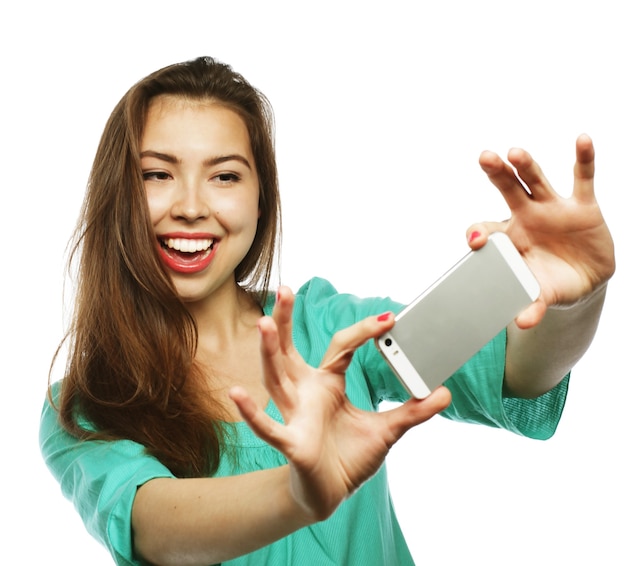 Koncepcja ludzie, styl życia i technologia: ładna nastolatka w zielonej koszuli, robi selfie swoim smartfonem - na białym tle