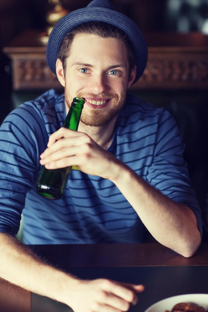 koncepcja ludzie, wypoczynek, uroczystości i wieczór kawalerski - szczęśliwy młody człowiek pijący piwo w barze lub pubie