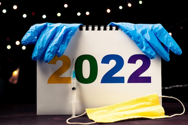 Koncepcja medycyny i 2022 r. Liczby i rękawiczki medyczne maskują strzykawkę