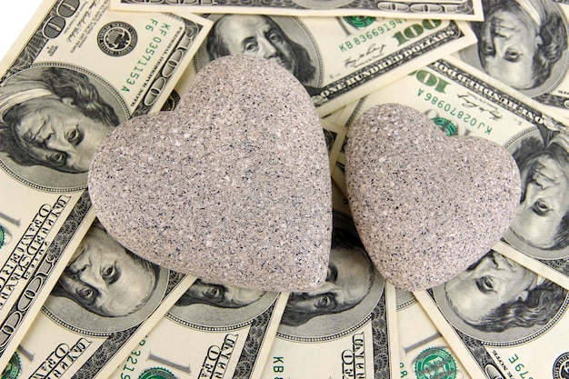Koncepcja miłości i pieniędzy. Kamień w kształcie serca i amerykańska waluta z bliska.