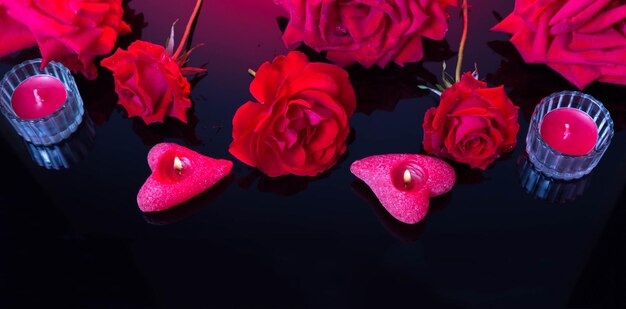 Koncepcja miłości i walentynek wykonana z czerwonych róż i świec na czarnym tle