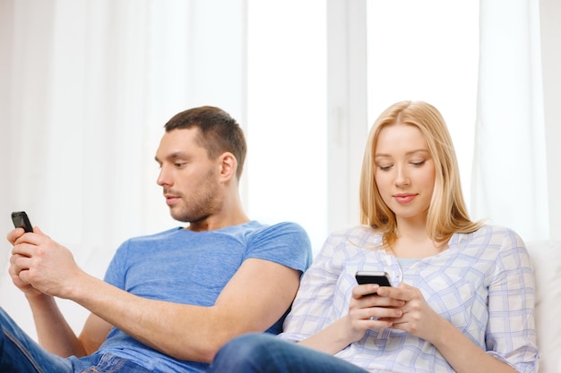 koncepcja miłości, rodziny, technologii, internetu i szczęścia - skoncentrowana para ze smartfonami w domu