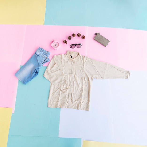 Zdjęcie koncepcja moda tło. koszula damska, niebieskie spodnie, torebka damska na kolorowym pastelowym tle papieru