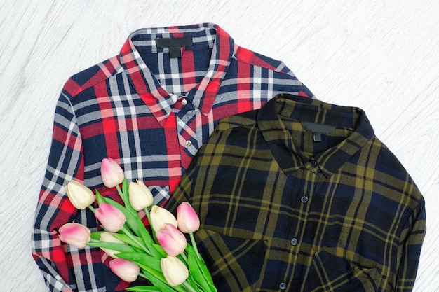 Koncepcja mody. Dwie koszule w kratkę i różowe tulipany. Drewniane tła
