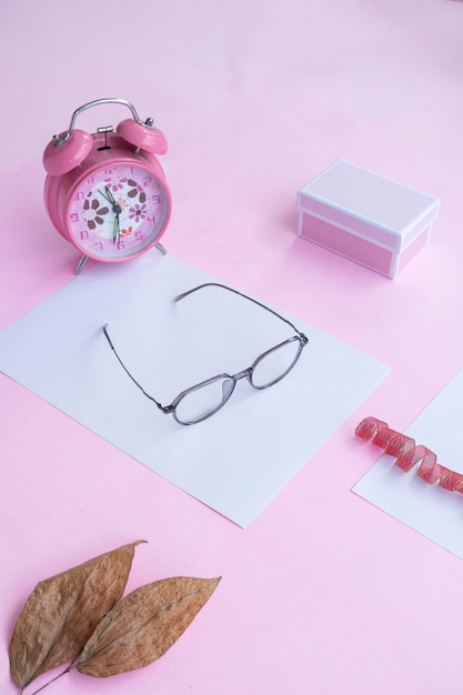 Koncepcja mody i urody leżąca płasko z kwadratowymi okularami damskimi akcesoriami na różowym tle
