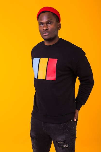 Koncepcja mody ulicznej - Studio strzał młodego przystojnego mężczyzny afrykańskiego na sobie bluzę przed żółtym